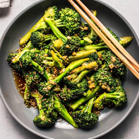 Overhead shot of broccoli stir fry in grey bowl with chopsticks.