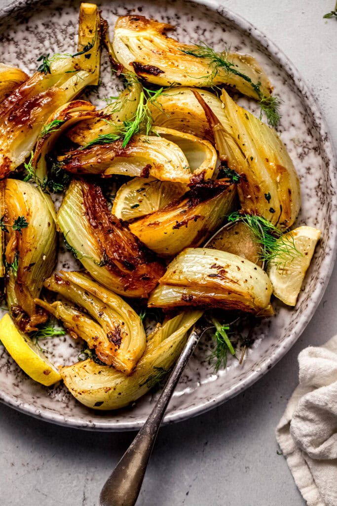 Braised fennel on grey plate with serving spoon. 