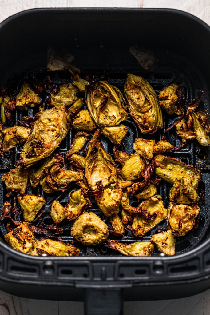 Crispy artichoke hearts in air fryer basket. 