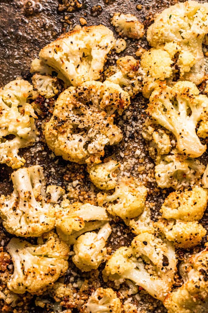 Roasted cacio e pepe cauliflower florets on baking sheet.