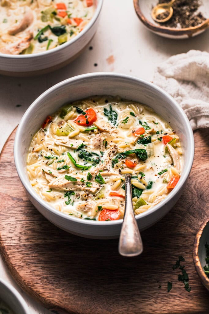 Side view of bowl of chicken orzo soup with heavy cream.