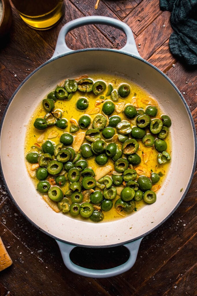 Green olives being cooked in olive oil.