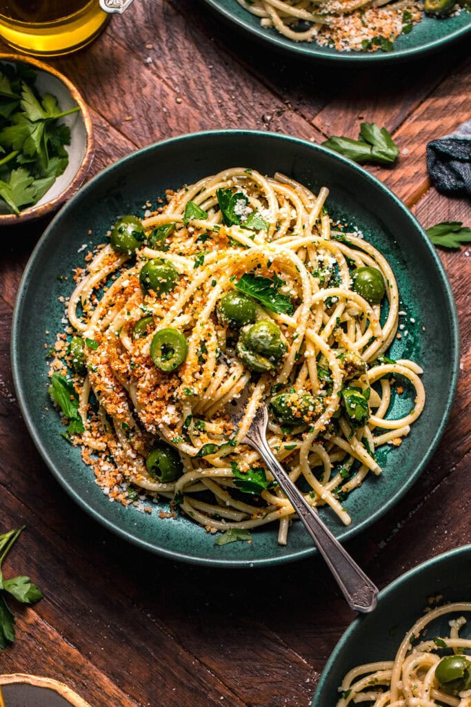 Bowl of olive pasta on wooden countertop.