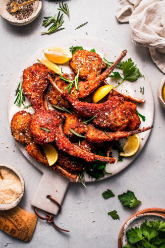Crispy fried parmesan coated lamb lollipops on serving plate.