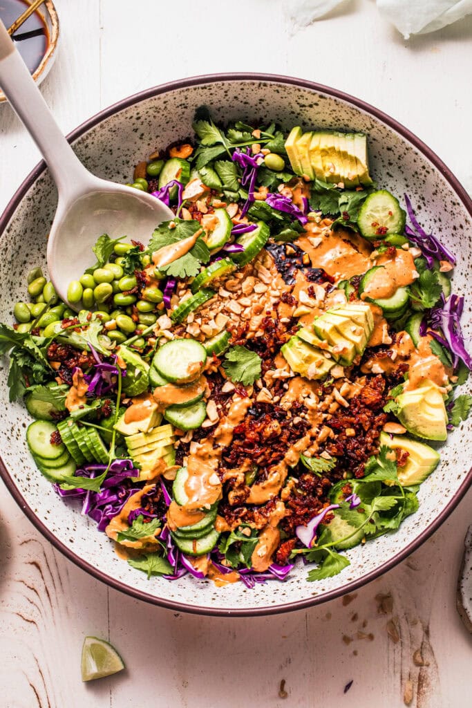 Prepared crispy rice salad in serving bowl with tongs.