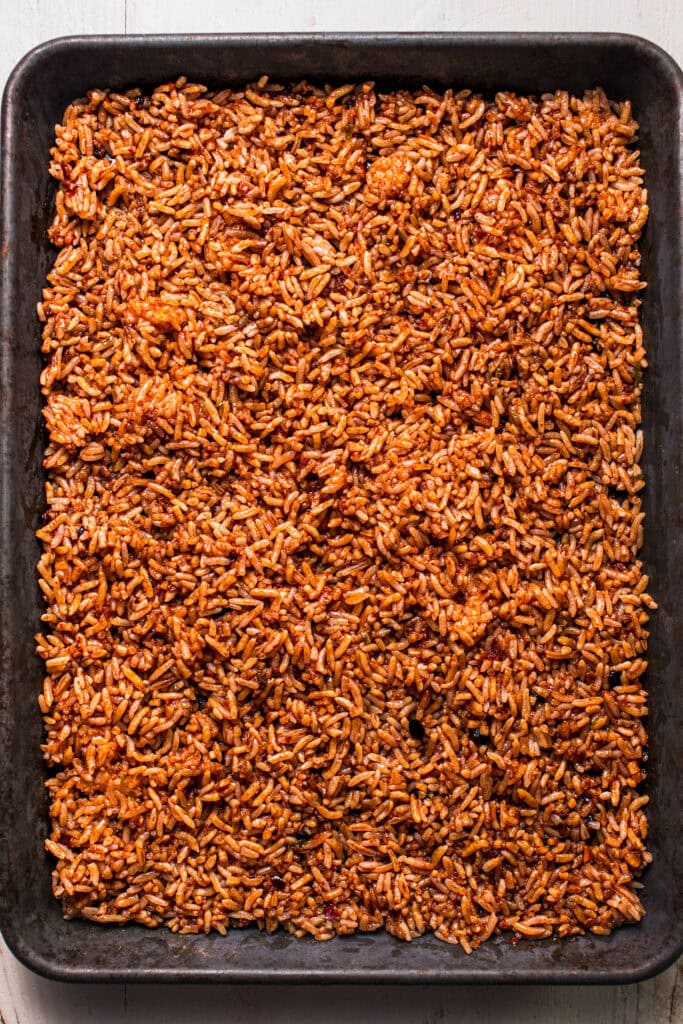 Rice spread out on baking sheet.