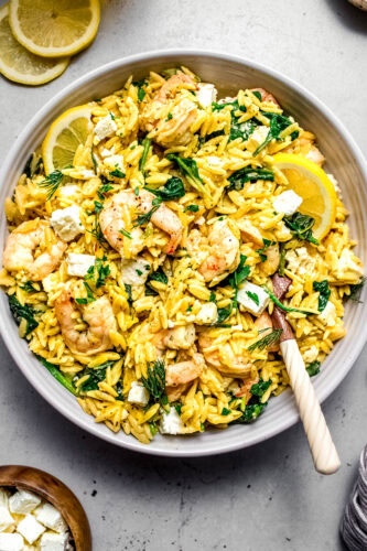Overhead shot of lemon shrimp orzo in serving bowl with spoons.