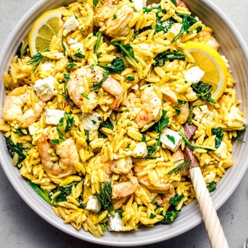 Overhead shot of lemon shrimp orzo in serving bowl with spoons.
