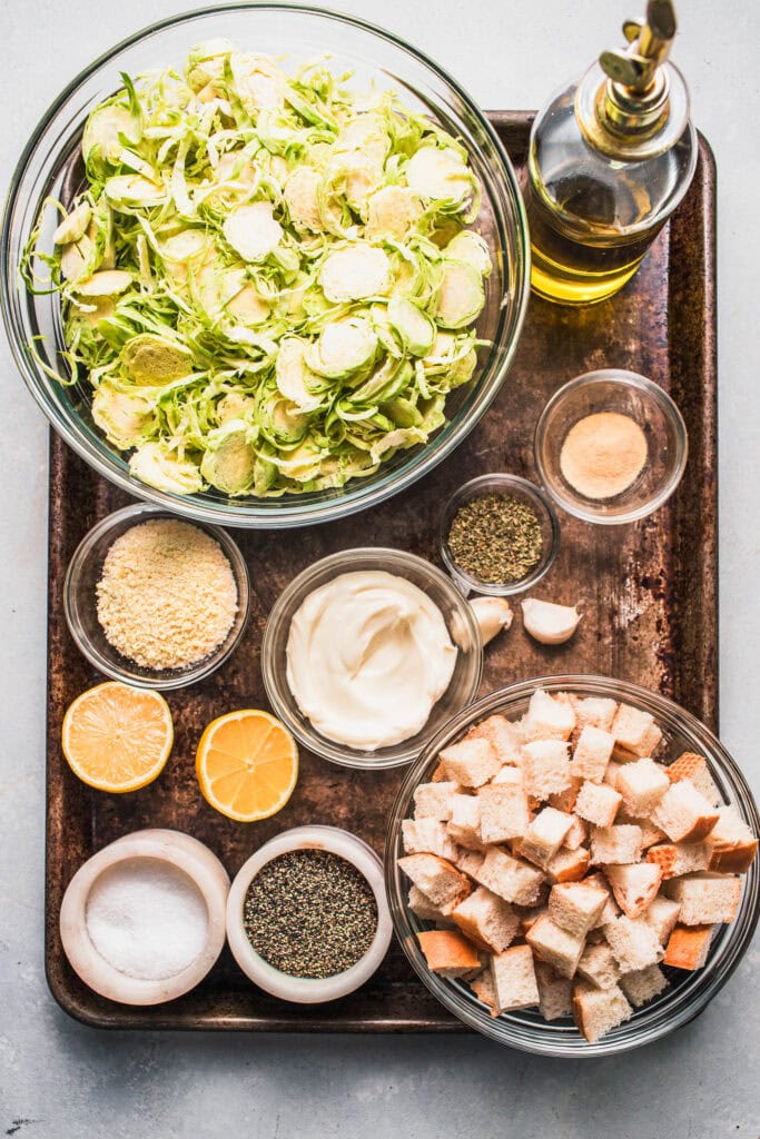 Ingredients for brussels sprouts caesar salad on tray. 