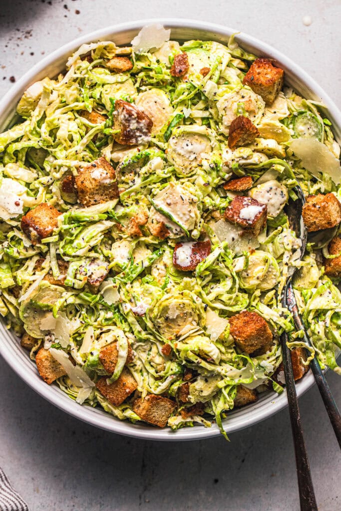 Overhead close up of prepared brussel sprout caesar salad in bowl. 