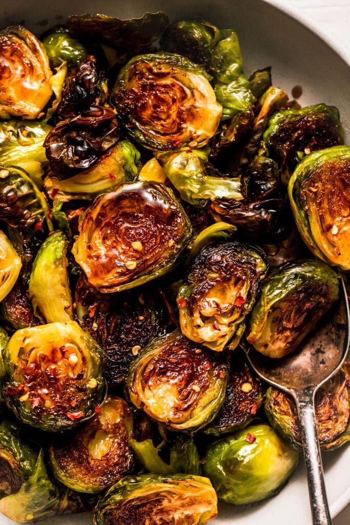 Overhead close up of Honey roasted brussel sprouts in bowl with serving spoon. 
