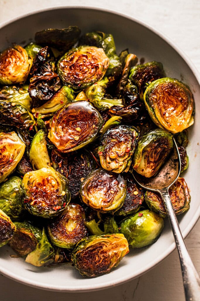 Balsamic honey brussel sprouts in serving bowl with spoon. 