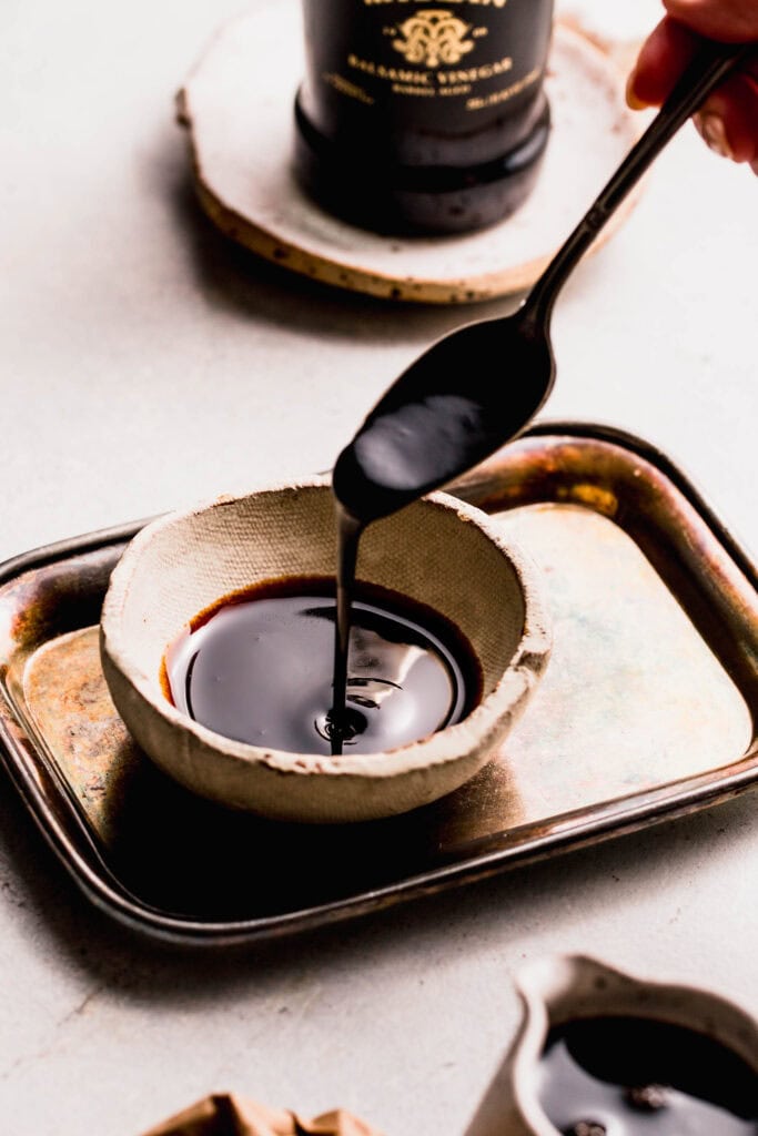 Spoon drizzling balsamic reduction into small bowl.