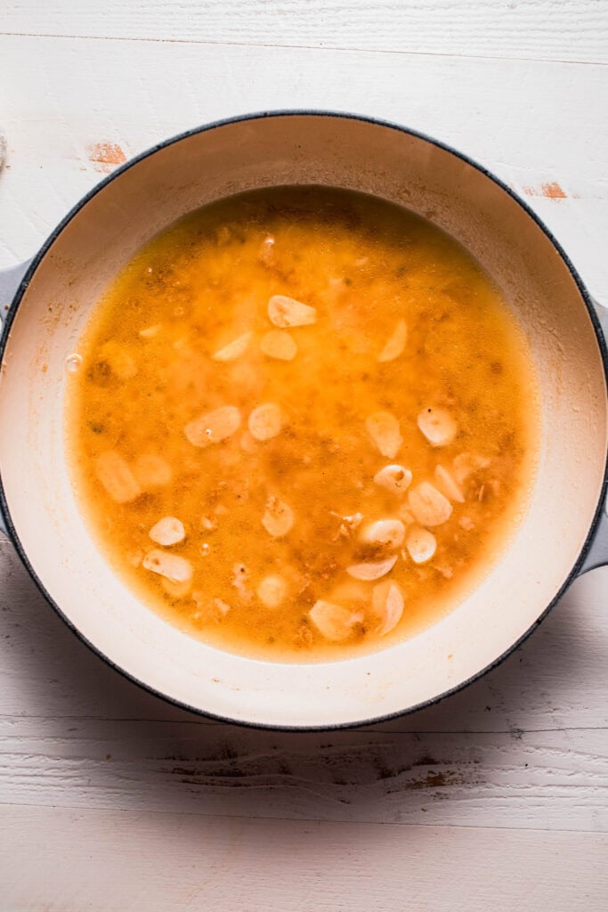 Garlic simmering in skillet with broth.
