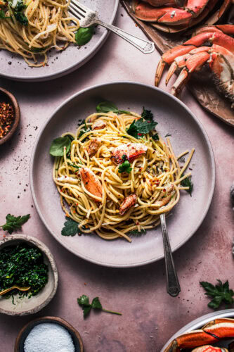 Overhead close up of bowl of crab spaghetti topped with lump crab pieces and parsley gremolata.