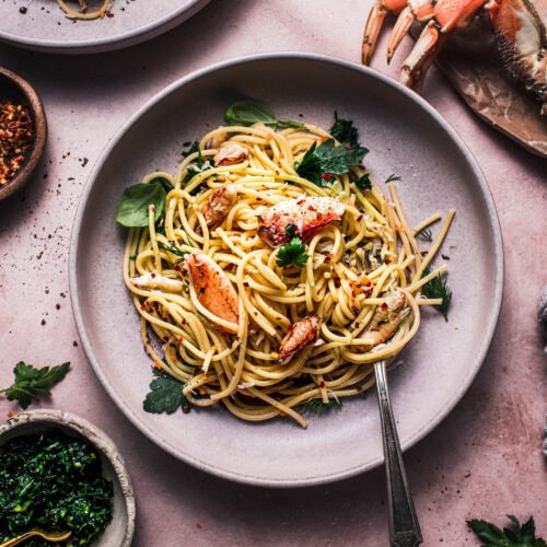 Overhead close up of bowl of crab spaghetti topped with lump crab pieces and parsley gremolata.