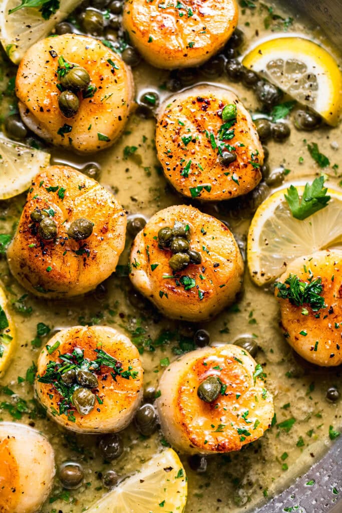 Sous vide scallops in skillet with lemon caper sauce.
