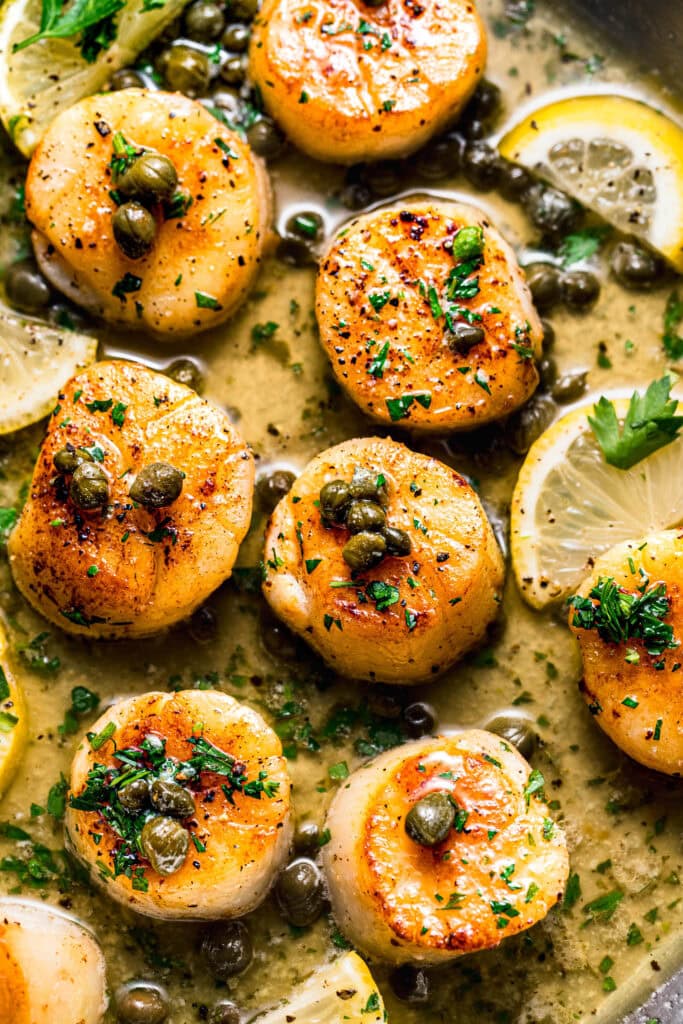 Sous vide scallops in skillet with lemon caper sauce.
