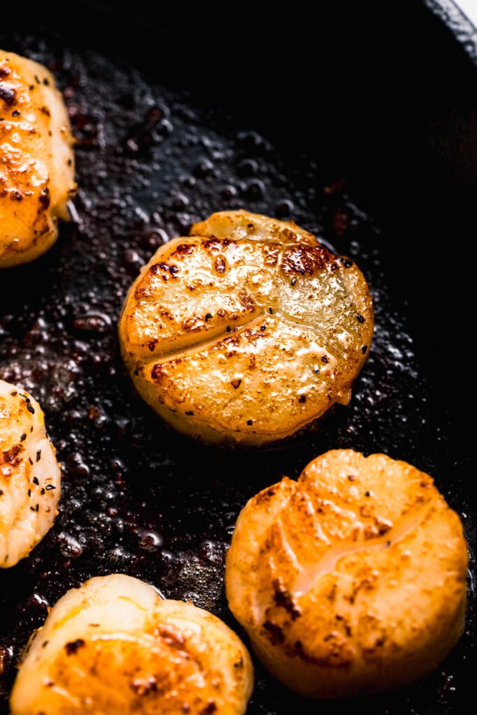Scallop searing in skillet.