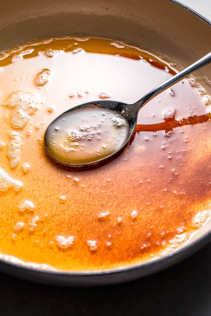 Spoon dipping into skillet of brown butter. 