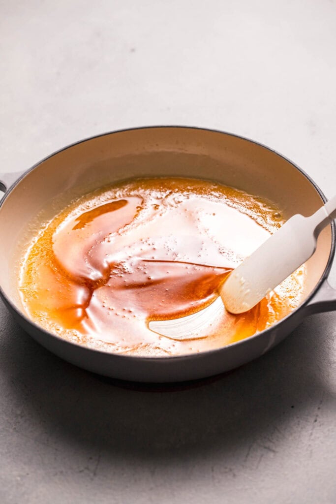 Hand stirring browned butter in skillet. 