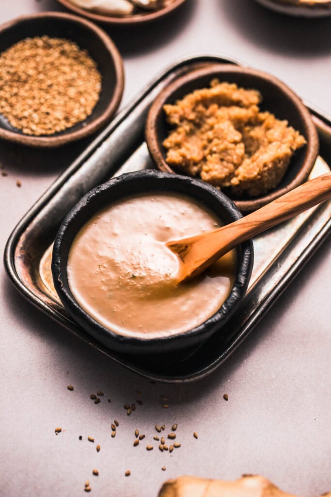 Side view of bowl of miso sauce next to bowl of miso paste.