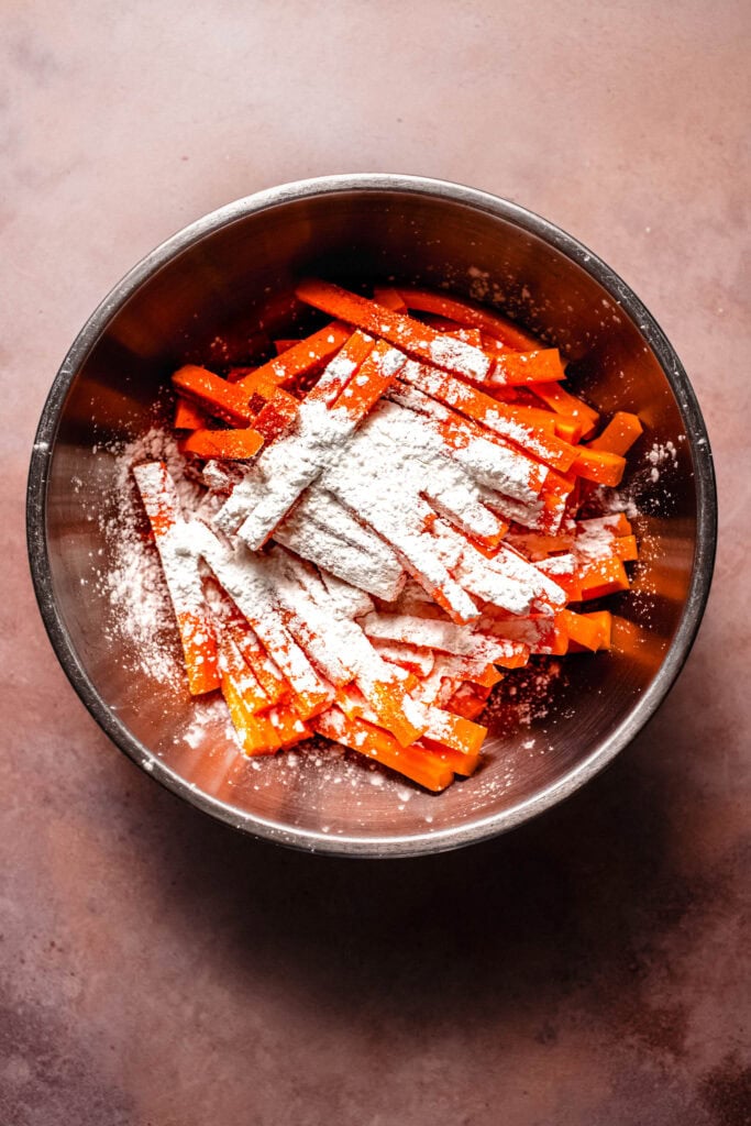 Carrot sticks being tossed with cornstarch.