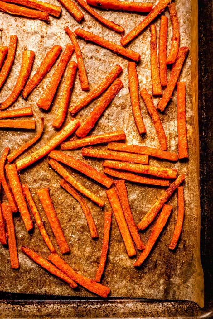 Close up of Baked carrot fries on baking sheet.