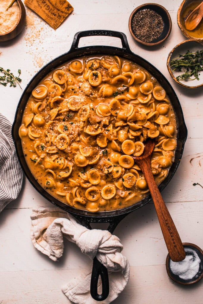 Finished french onion pasta in skillet with wooden spoon.