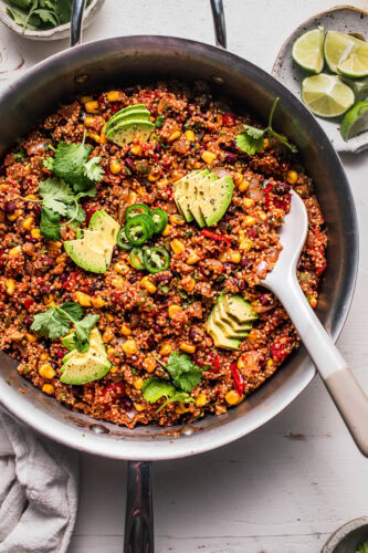 Spoon digging into skillet of Mexican quinoa.