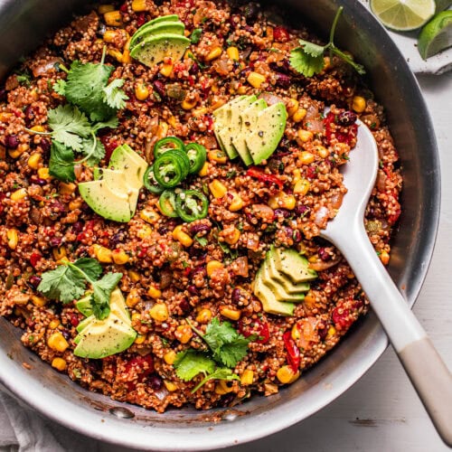 Spoon digging into skillet of Mexican quinoa.