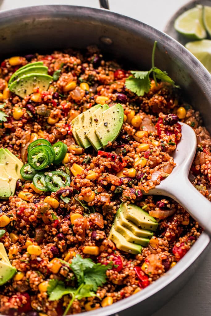 Side view of Spoon digging into skillet of Mexican quinoa.