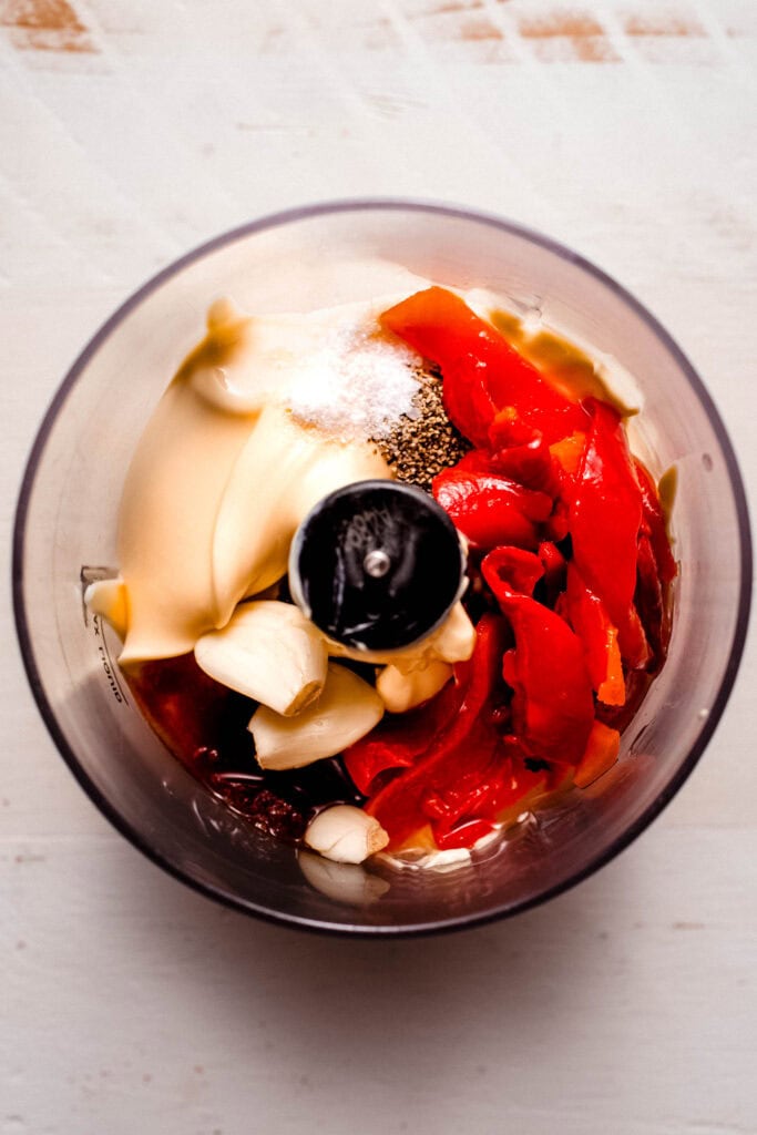 Ingredients for roasted pepper aioli in food processor bowl before blending.