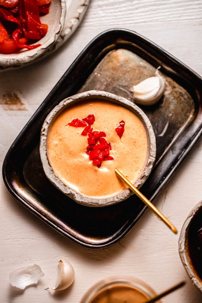Bowl of red pepper aioli topped with chopped roasted red peppers.