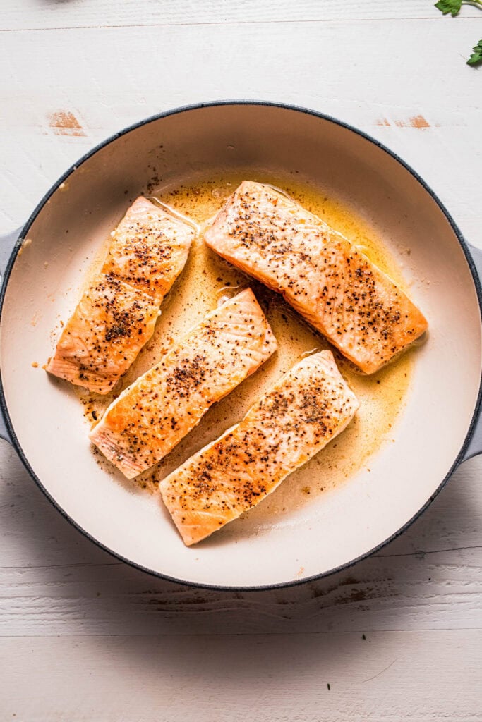 Salmon filets browning in skillet.