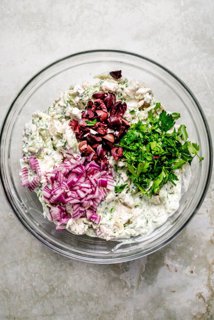 Tzatziki chicken salad ingredients being combined in large bowl.
