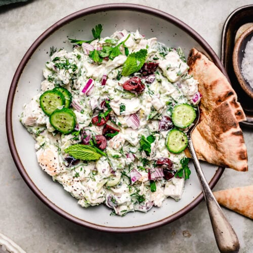 Bowl of homemade tzatziki chicken salad photographed from above, finished with cucumber slices and mint.