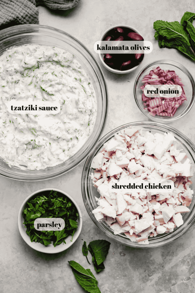 Ingredients for tzatziki chicken salad labeled on counter. 
