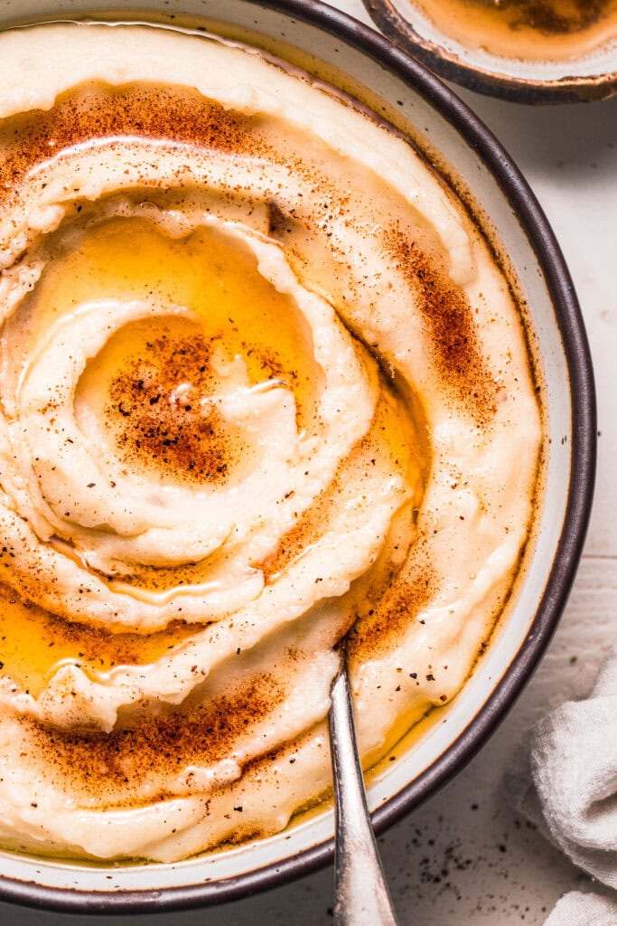 Extreme close up of browned butter mashed potatoes in serving bowl with spoon.