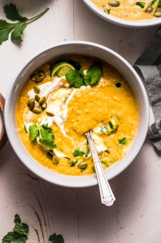 Overhead shot of creamy poblano soup that is swirled with sour cream and topped with pepitas.