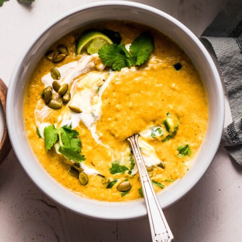 Overhead shot of creamy poblano soup that is swirled with sour cream and topped with pepitas.