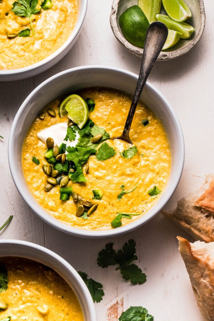 Spoon dipping into bowl of creamy poblano soup.
