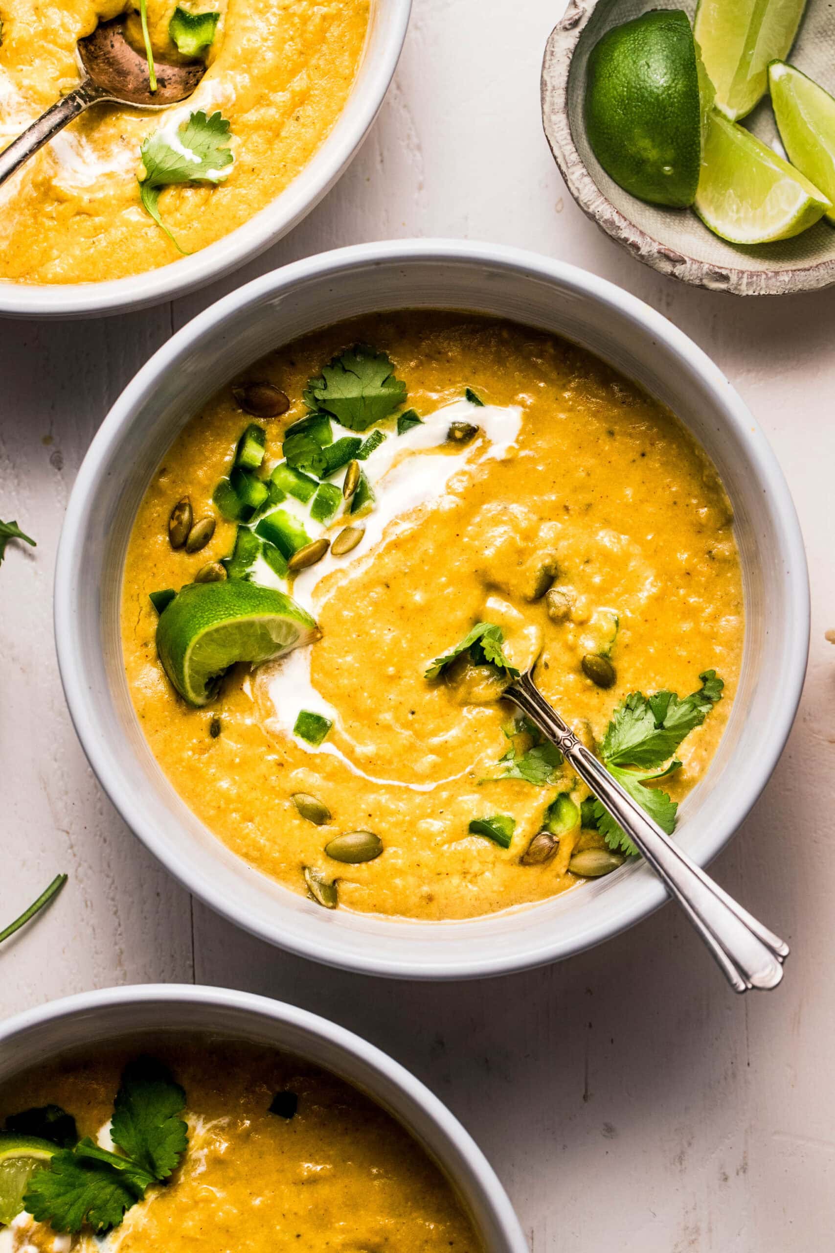 Overhead shot of creamy poblano soup that is swirled with sour cream and topped with pepitas.