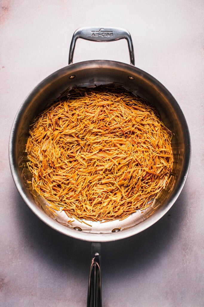 Fideos being toasted in skillet.