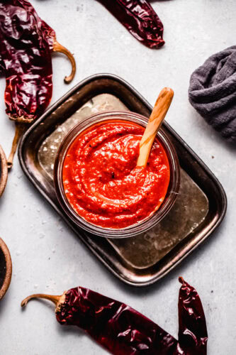 Overhead shot of finished Guajillo sauce in glass bowl with wooden spoon.
