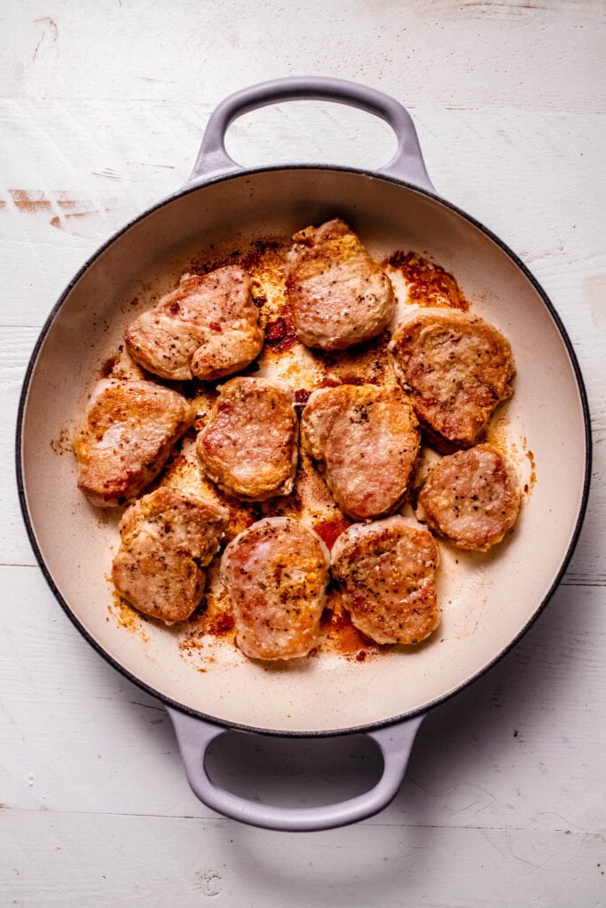 Browned pork medallions in skillet.