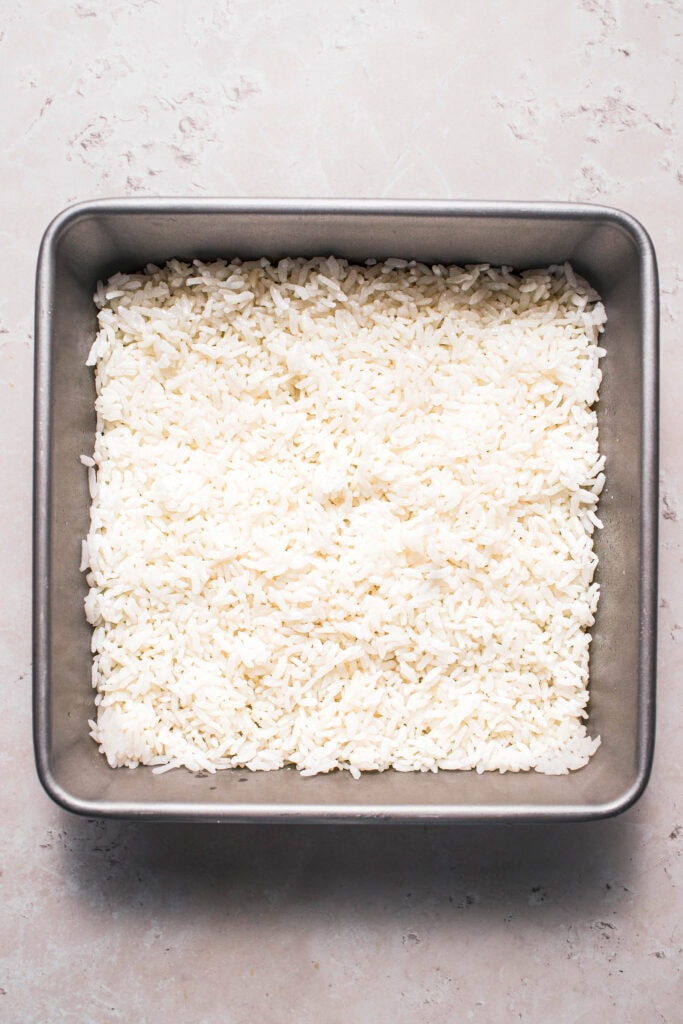 Sushi rice pressed into baking pan.