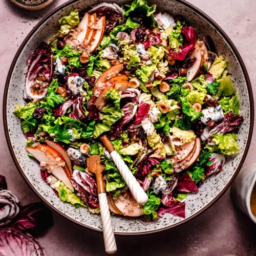 Overhead shot of assembled Thanksgiving salad topped with pears, purple chicories and blue cheese.