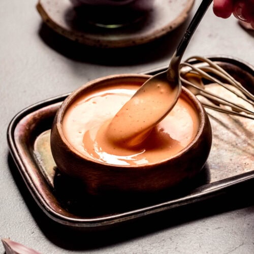 Spoon dipping into small bowl of bbq aioli.