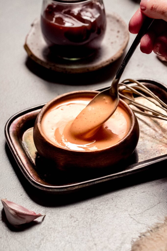 Spoon dipping into small bowl of bbq aioli.